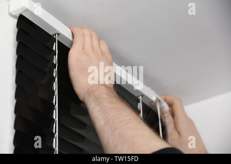 Male hands installing window blinds Stock Photo