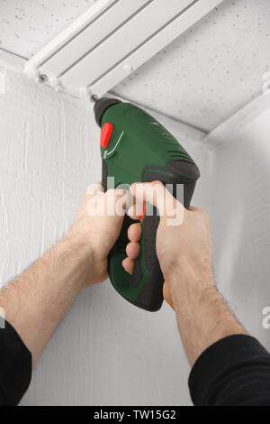 Male hands installing curtain rail using electric screwdriver Stock Photo