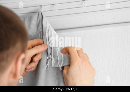 Male hands installing curtains over window Stock Photo