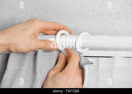 Male hands installing curtains over window Stock Photo