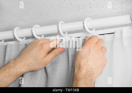 Male hands installing curtains over window Stock Photo