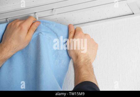 Male hands installing curtains over window Stock Photo