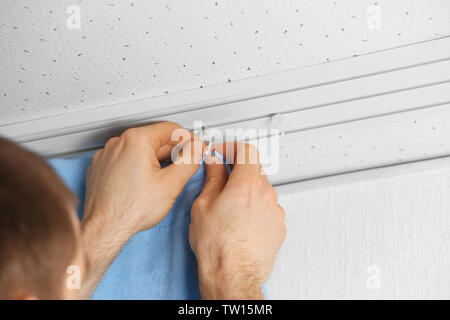 Male hands installing curtains over window Stock Photo