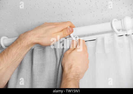 Male hands installing curtains over window Stock Photo