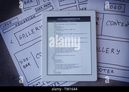 Tablet with programming code for website on table Stock Photo