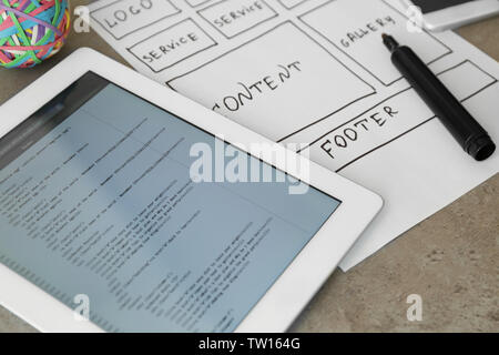 Tablet with programming code for website on table Stock Photo