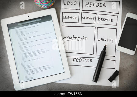 Tablet with programming code for website on table Stock Photo