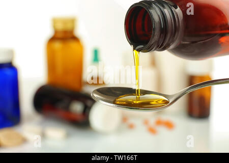 Pouring cough syrup into spoon on blurred background of medicines Stock Photo