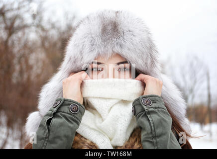 Young beautiful woman covering face with scarf in winter park Stock Photo