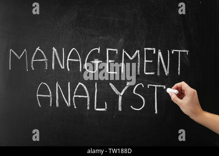 Hand writing phrase MANAGEMENT ANALYST on blackboard Stock Photo