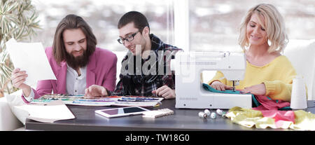 Smiling tailor businesswoman sitting at sewing machine Stock Photo