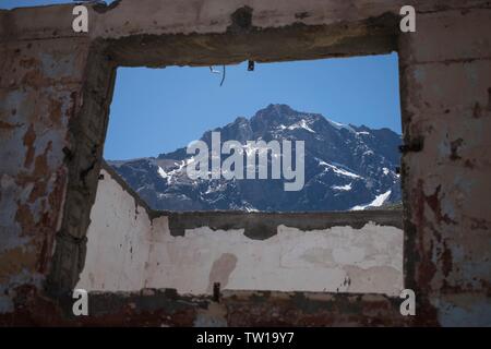 Beautiful rocky mountain seen through a square shaped opening from a stone building Stock Photo