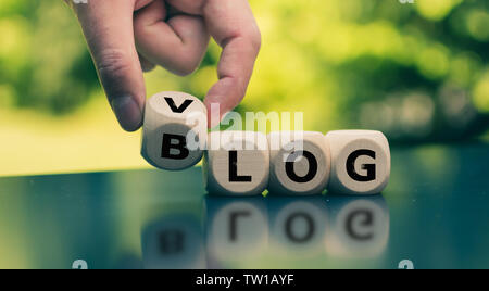 Blog or Vlog? Hand turns a cube and changes the expression "BLOG" to "VLOG" (or vice versa). Stock Photo