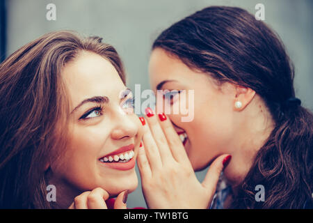 Shot of a young beautiful woman whispering something to her friends ear in a cafe. Stock Photo
