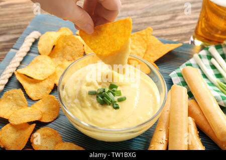 Woman hand dipping nacho in beer cheese dip Stock Photo