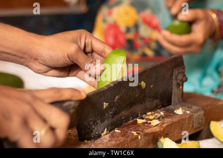 Closeuof Handing cutting ripe Mango for making Picke In India with Indian vegetable cutter Stock Photo