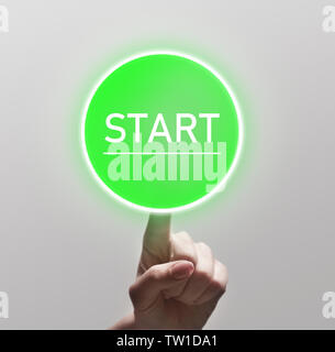 Finger touching green start button on light background, copy space Stock Photo