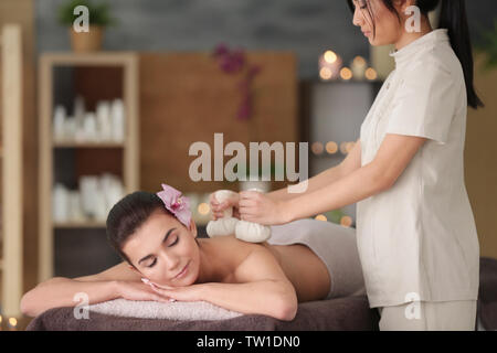 Beautiful young woman having massage with herbal compress balls in spa salon Stock Photo