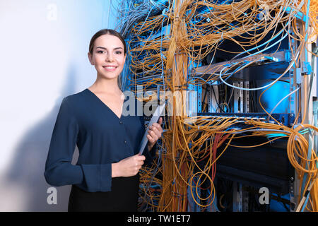 Beautiful young engineer with clipboard in server room Stock Photo