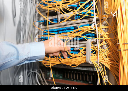 Hand of young engineer connecting cables in server room Stock Photo