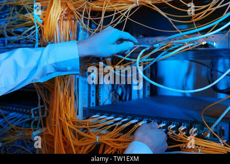 Hands of young engineer connecting cables in server room Stock Photo