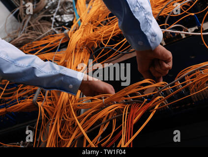 Hands of young engineer connecting cables in server room Stock Photo