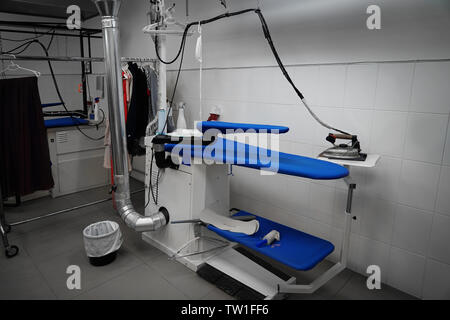 Professional ironing board in dry cleaner's workshop Stock Photo