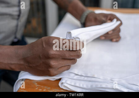 Waiter folds napkins in restaurant. Waiters hands with white napkin close up Stock Photo