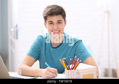 Teenager sitting at table and taking notes at home Stock Photo