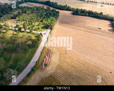 Nature and landscape, aerial view of fields with tractor with round baler and tractor with a rake, machines for collecting and pressing hay. Stock Photo