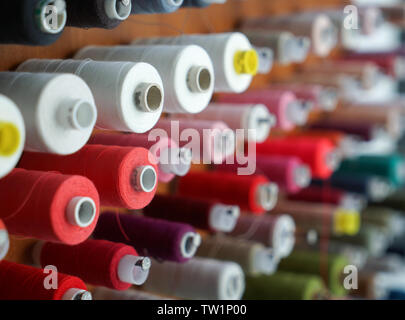 Spools with colorful threads on rack, closeup Stock Photo