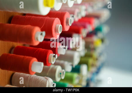 Spools with colorful threads on rack, closeup Stock Photo