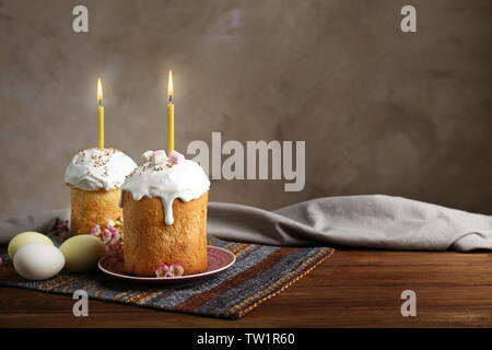 Two Easter cakes with lighted candles on wooden table Stock Photo