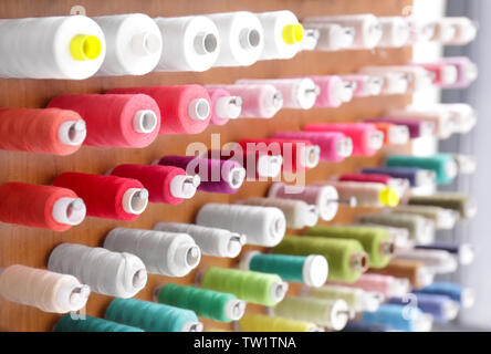 Spools with threads on rack, closeup Stock Photo