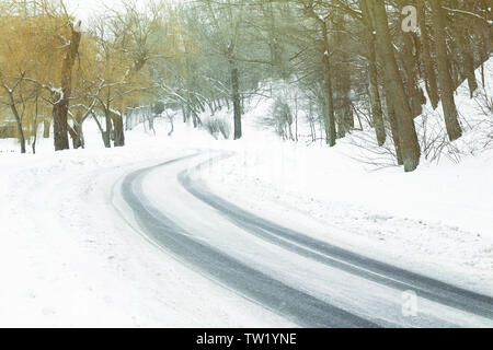 Traces of tires on snow covered road bend in winter time Stock Photo
