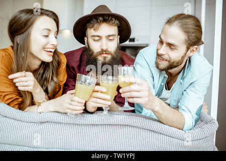 Portrait of a young and cheerful friends dressed casually sitting together on the couch at home Stock Photo