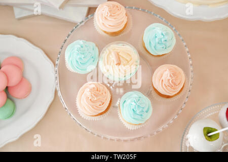Glass stand with beautiful tasty cupcakes on table Stock Photo