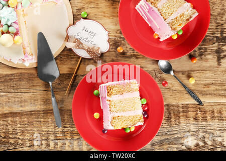 Two red plates with Easter cake slices on wooden background Stock Photo