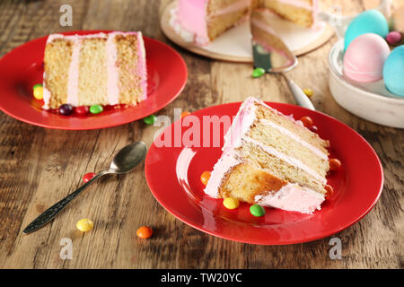 Two red plates with Easter cake slices on wooden background Stock Photo