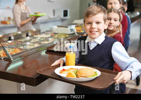 Cute girl holding tray with delicious food in school cafeteria Stock Photo