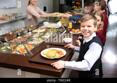 Cute little boy receiving food in school cafeteria