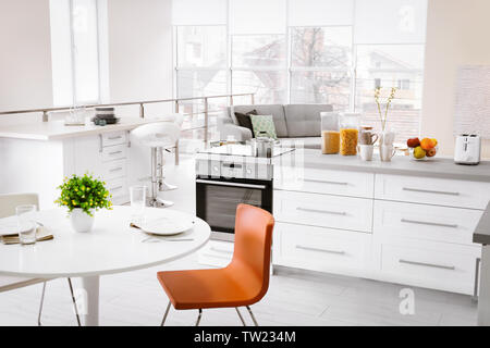 Modern kitchen interior of studio apartment with large counter and white round table Stock Photo
