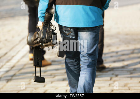 Walking man holding professional camcorder outdoors Stock Photo