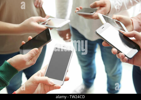Young people standing in circle and using smartphones Stock Photo