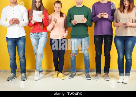 Young people using digital devices on color background Stock Photo