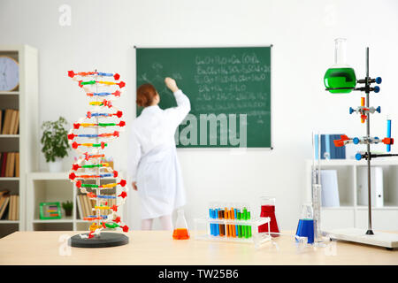 Workplace with different tools and school girl writing on blackboard in chemistry class Stock Photo