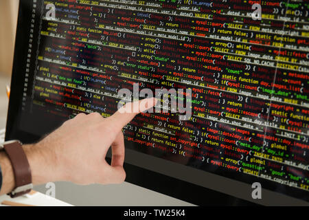 Male hand pointing on computer monitor with programming code, closeup Stock Photo