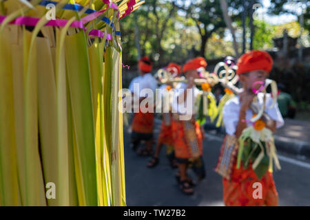 DENPASAR/BALI-JUNE 15 2019: Young Balinese boy wearing traditional Balinese headdress and traditional sarong bring sampian at the opening ceremony of Stock Photo