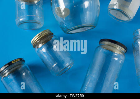 Transparent glass jars with lids isolated on blue background, top view flat lay recycling concept for environmental awareness. Segregated recyclables Stock Photo