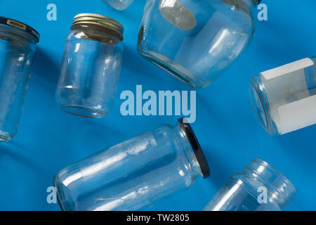 Transparent glass jars with lids isolated on blue background, top view flat lay recycling concept for environmental awareness. Segregated recyclables Stock Photo